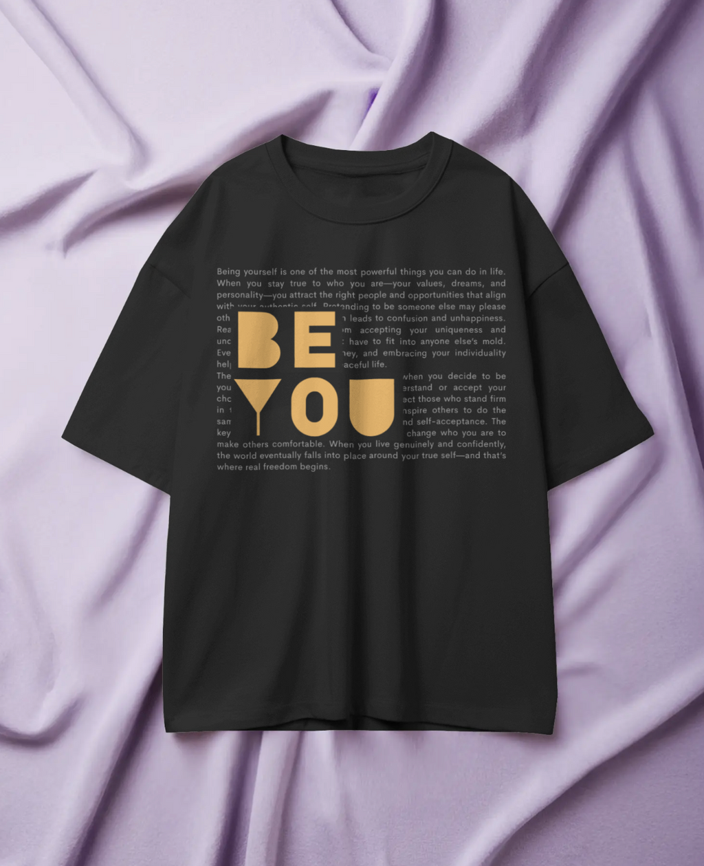Black t-shirt with 'BE YOU' text on a purple fabric background